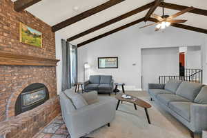 Living room with a brick fireplace, a ceiling fan, and light colored carpet