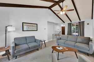 Living room featuring carpet floors, a ceiling fan, and vaulted ceiling