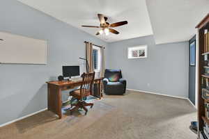 Office space with light carpet and a ceiling fan
