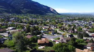 Aerial view of property and surrounding area featuring mountains and nearby suburban area
