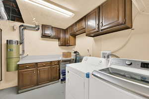 Laundry area with cabinet space, a textured ceiling, concrete floors, and separate washer and dryer