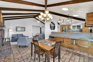 Dining space with vaulted ceiling, suspended lighting, and a brick fireplace