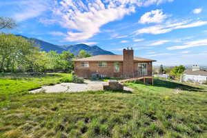 Back of house featuring a chimney, brick siding, a mountain view, and a patio area