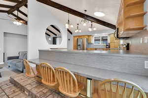 Kitchen featuring lofted ceiling, a peninsula, stainless steel appliances, light countertops, and suspended lighting