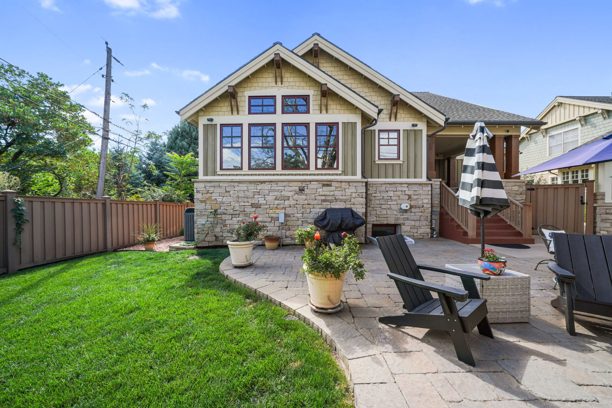 Back of house with a fenced backyard, a patio, stone siding, board and batten siding, and roof with shingles