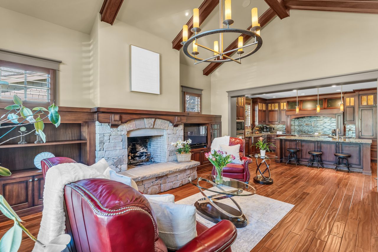 Living room with a fireplace, wood floors, and suspended lighting