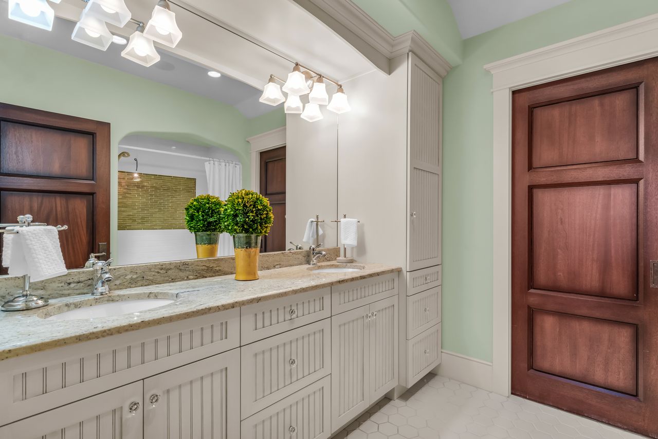 Bathroom featuring double vanity and a shower, additional laundry space behind door