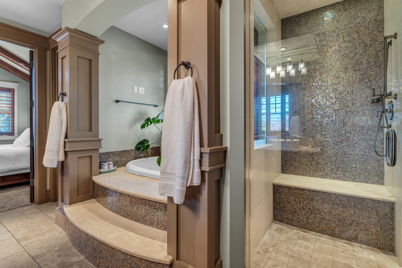 Ensuite bathroom featuring a shower stall, light tile patterned floors, and a soaking bath