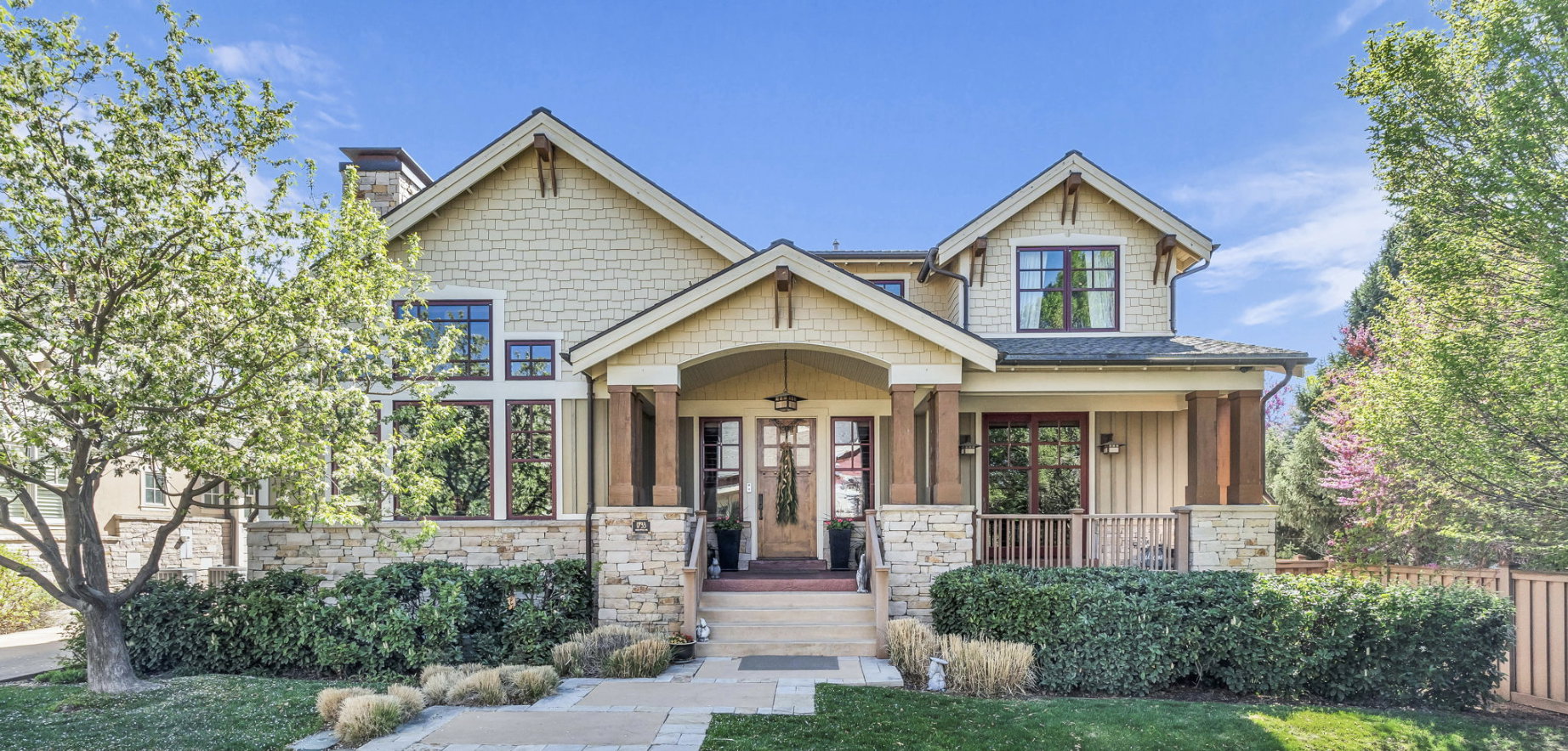 Craftsman house with stone siding, covered porch, board and batten siding, and a chimney