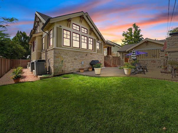 Rear view of house featuring stone siding and a patio