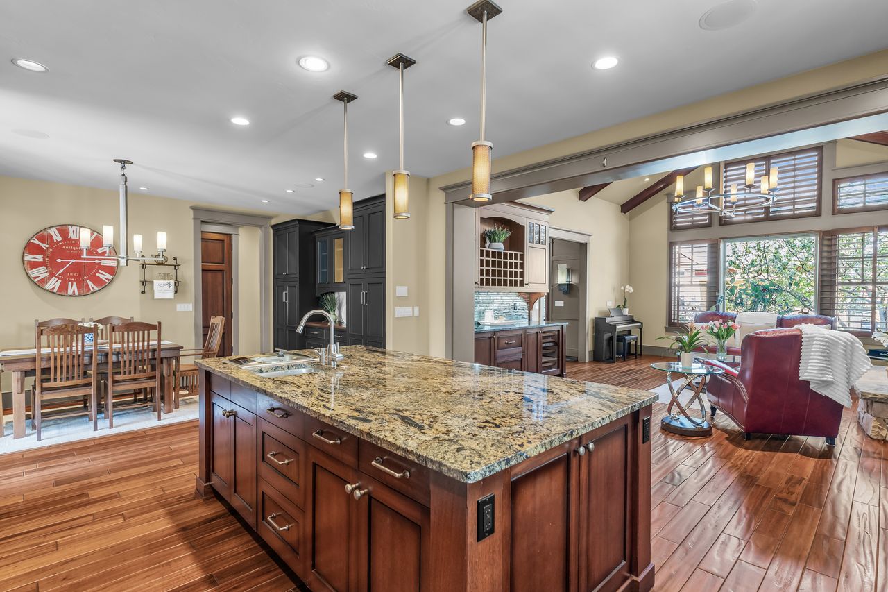 Kitchen with suspended lighting, light stone countertops, lofted ceiling with beams, open floor plan, and wood flooring