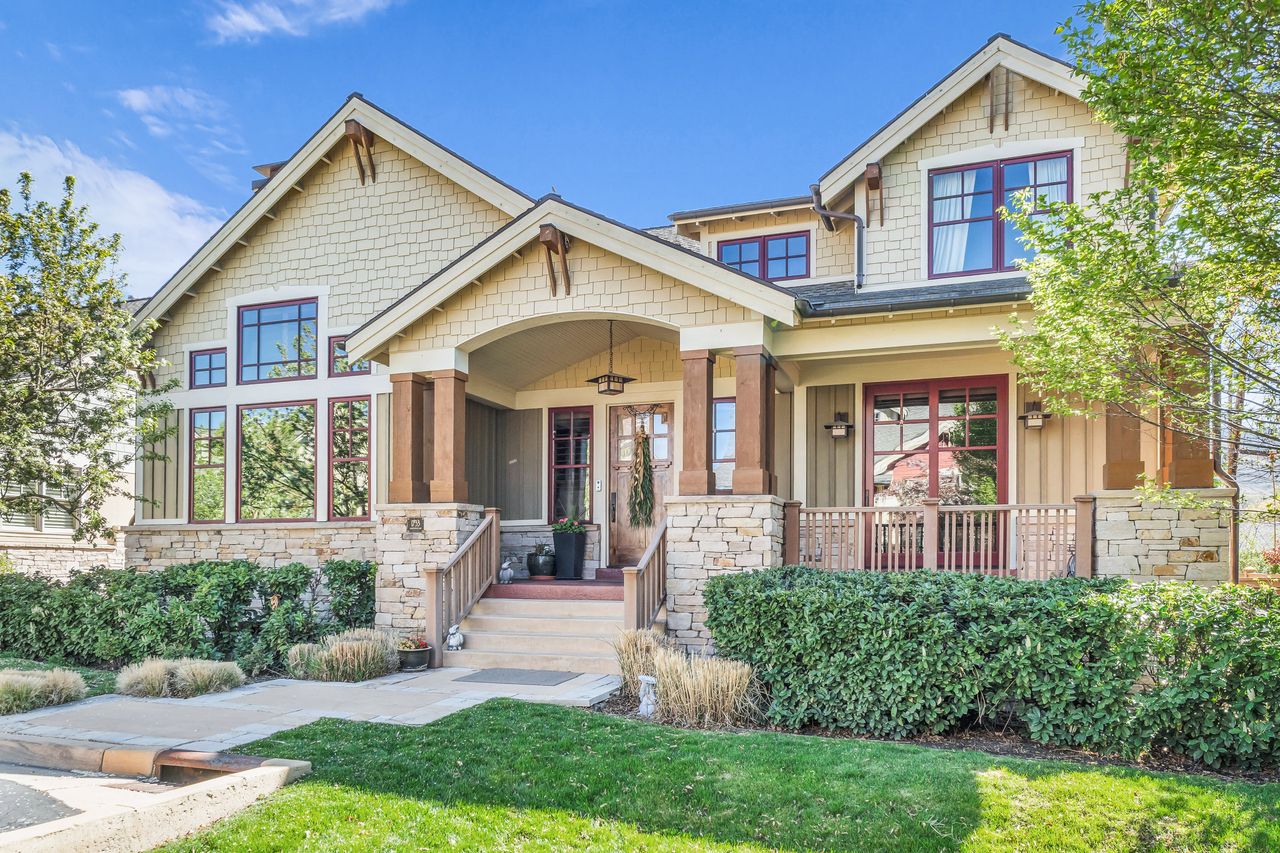 Craftsman house with covered porch, stone siding, board and batten siding, and a front yard