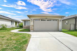 View of front of home featuring concrete driveway, a garage, and stone siding