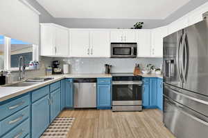 Kitchen featuring dual tone cabinets, stainless steel appliances, decorative backsplash, and light wood-type flooring
