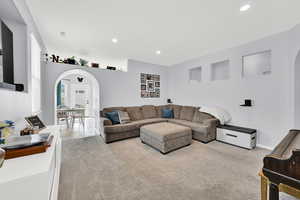 Living room featuring arched walkways, light carpet, and recessed lighting