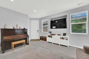 Sitting room with light carpet, healthy amount of natural light, and recessed lighting