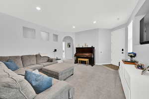 Living area with arched walkways, recessed lighting, and light carpet