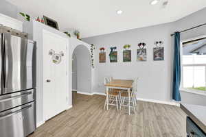 Dining area with arched walkways, wood finish floors, and recessed lighting