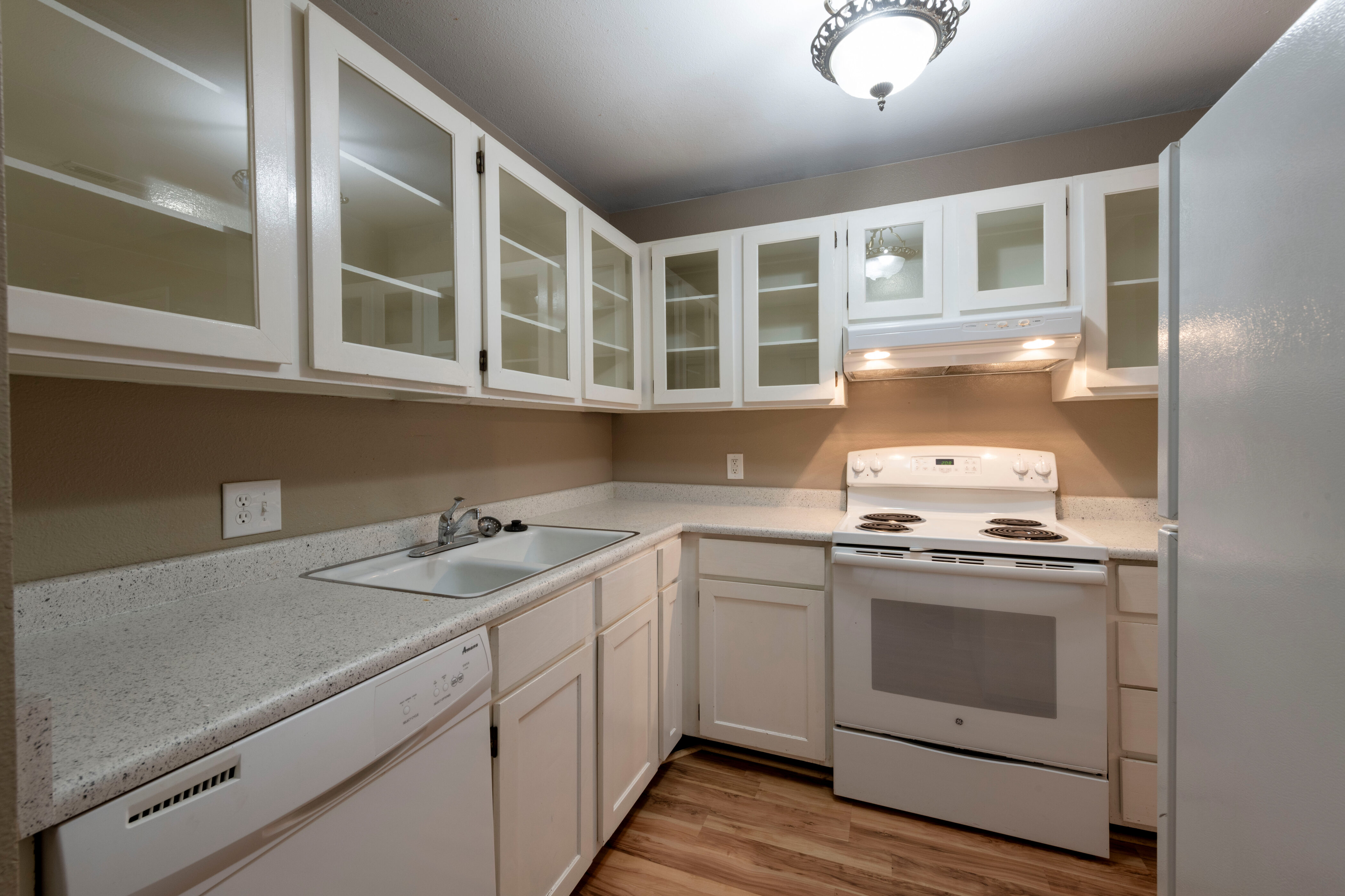 Kitchen featuring white cabinets, white appliances, light countertops, glass insert cabinets, and light wood finished floors