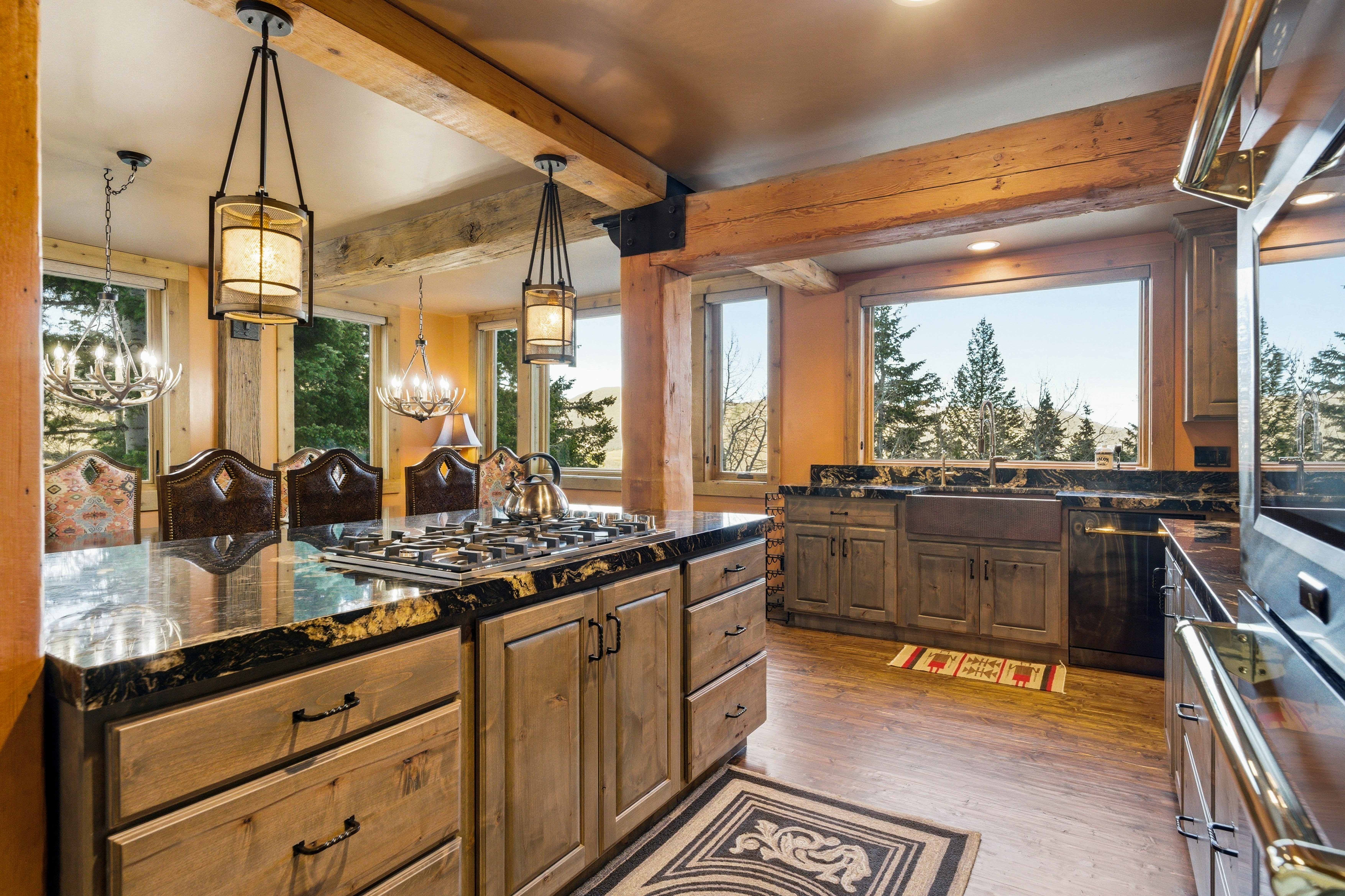 Kitchen with dark wood finished floors, pendant lighting, dark stone counters, dishwashing machine, and plenty of natural light