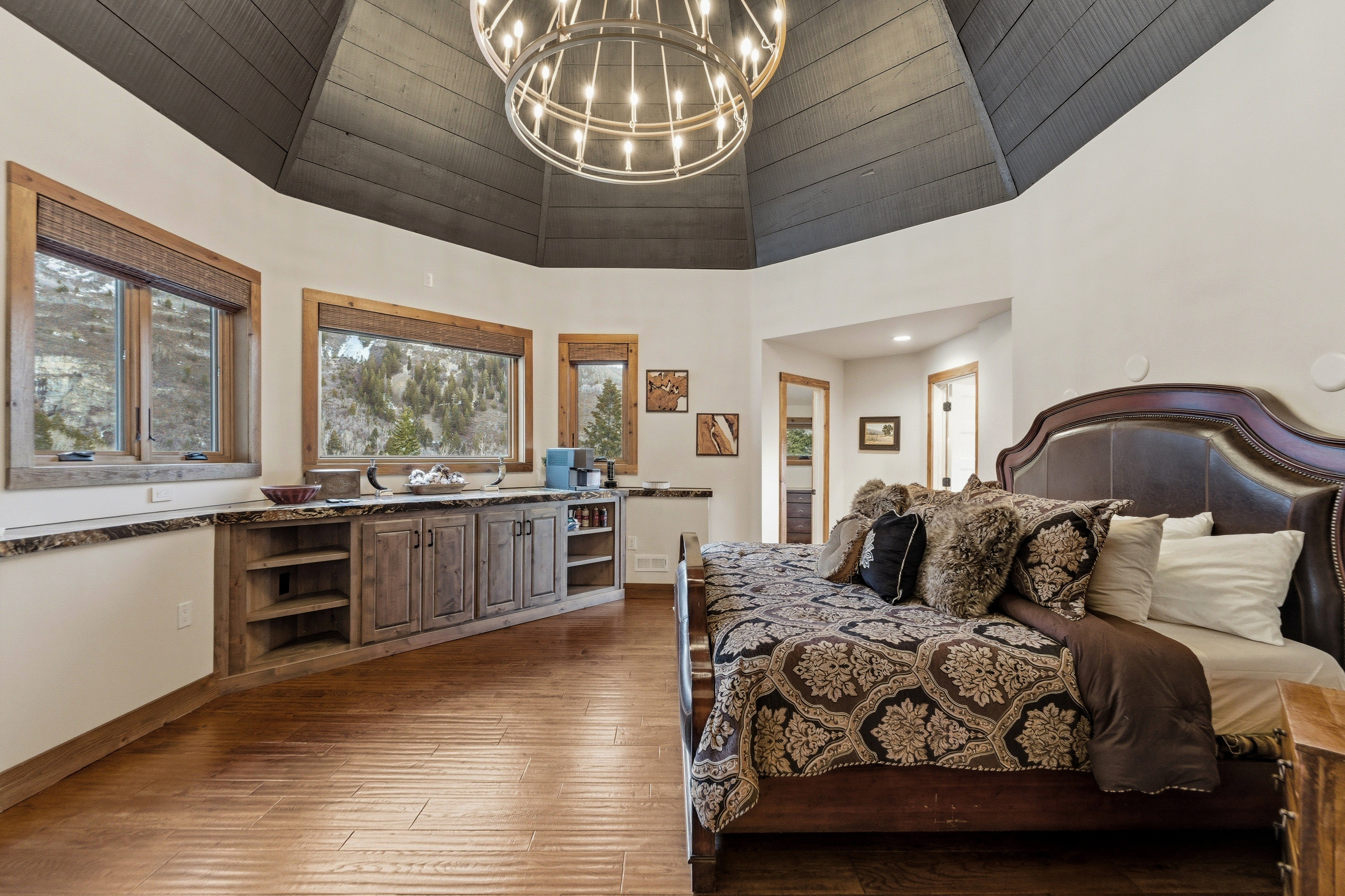 Bedroom featuring suspended lighting, dark wood finished floors, and vaulted ceiling