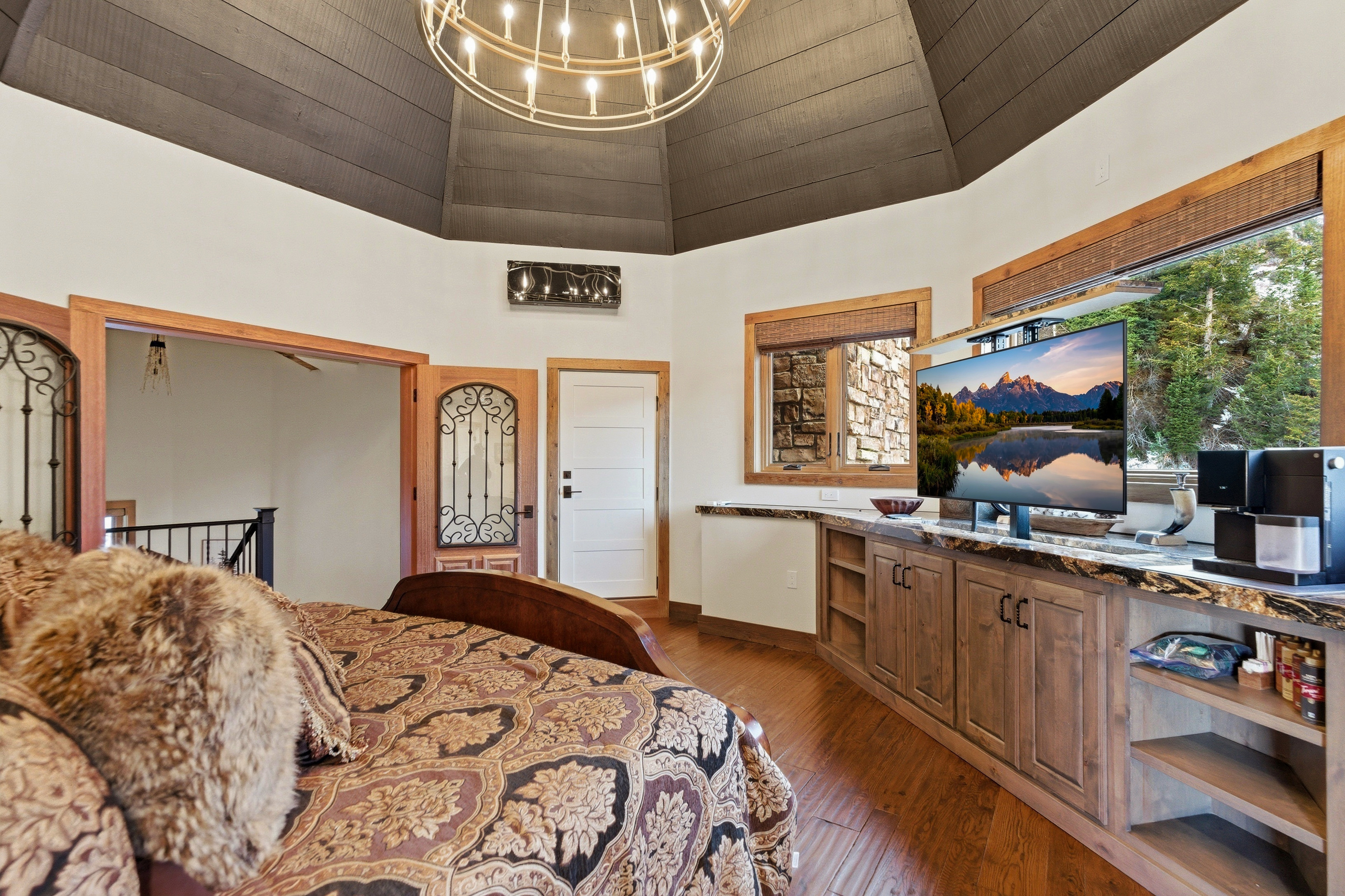 Bedroom featuring dark wood-style floors, hanging lights, and a high ceiling