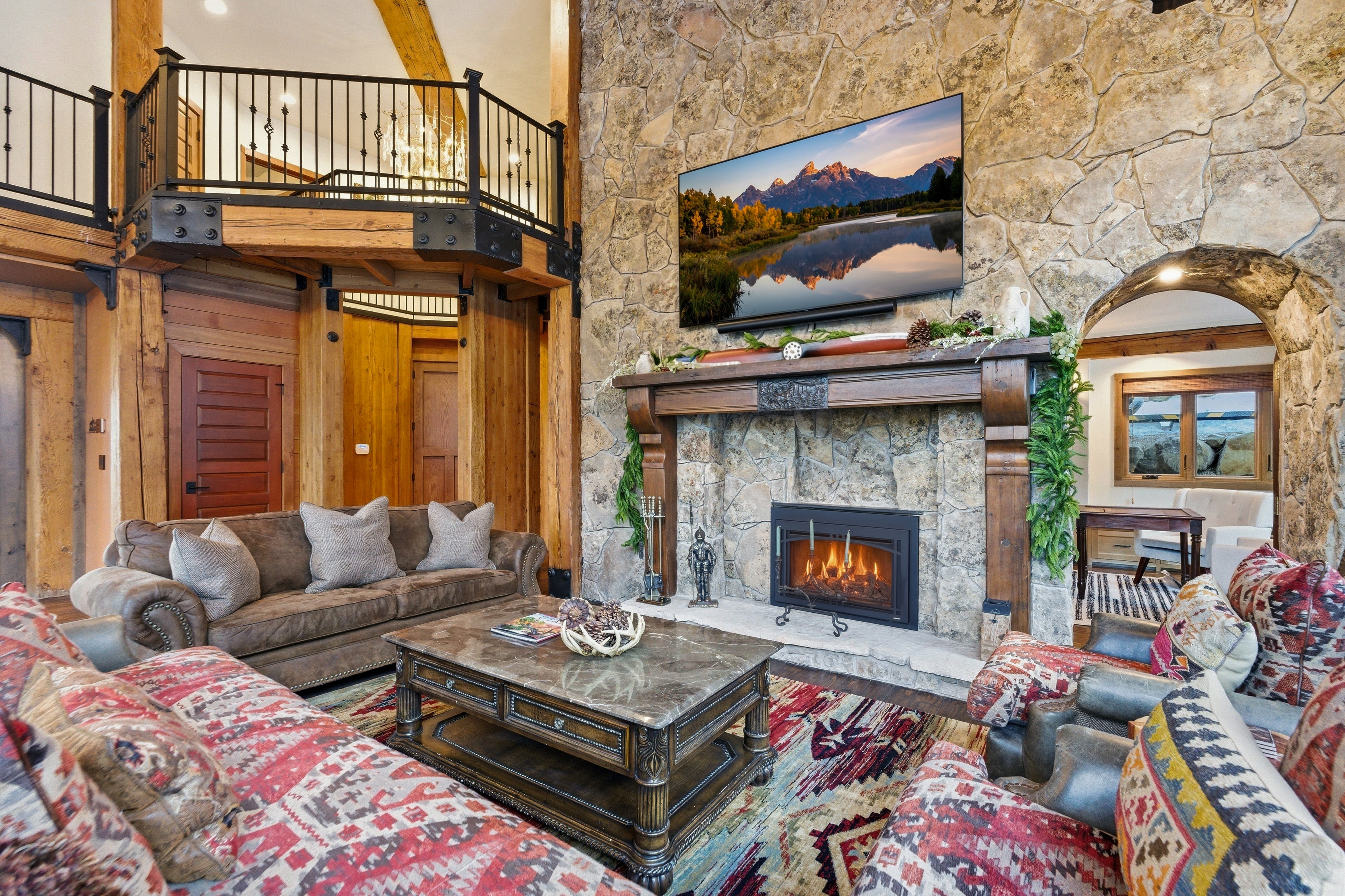 Living room featuring a stone fireplace, wood finished floors, and wooden walls