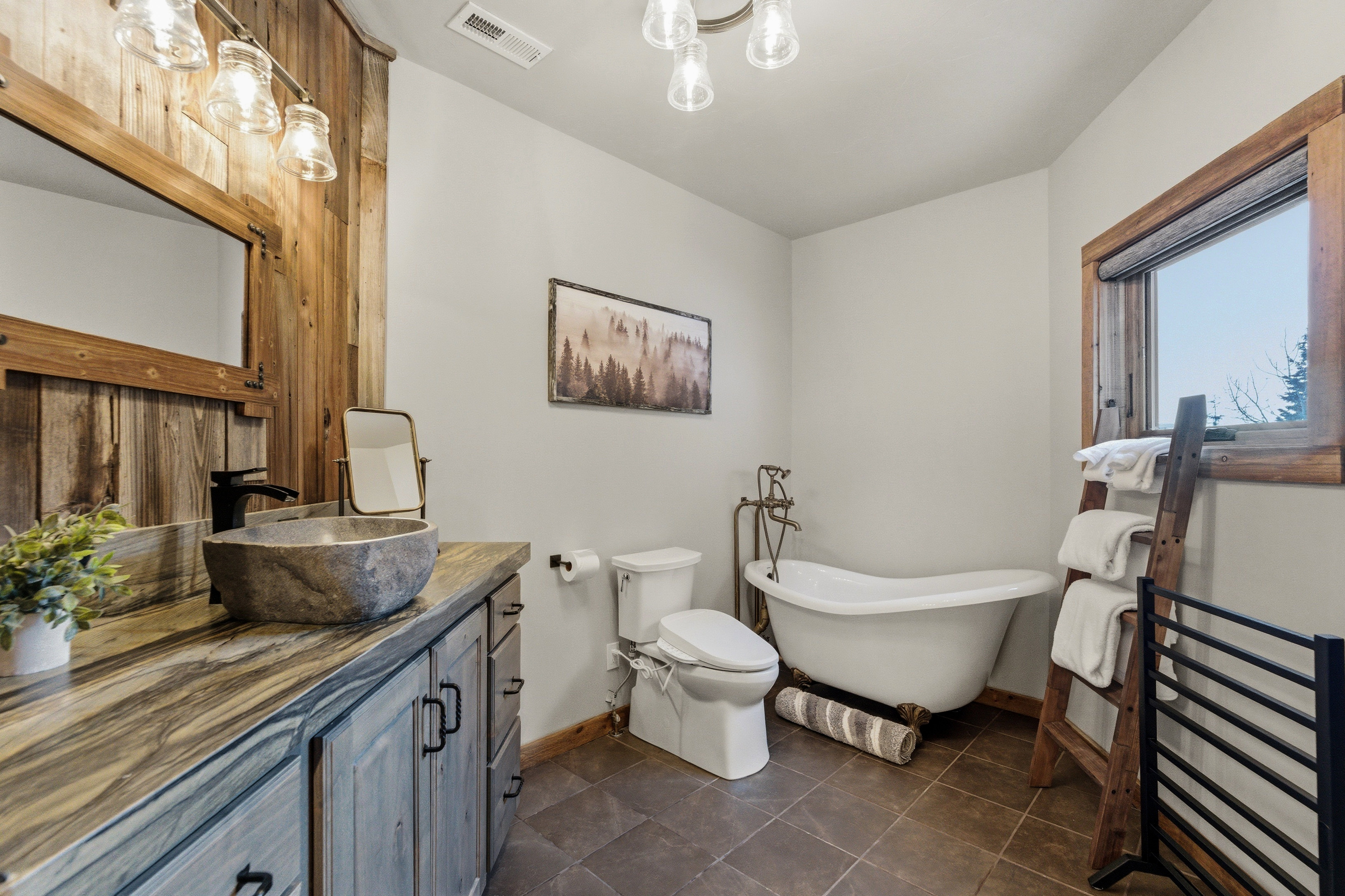 Full bathroom with a soaking tub, vanity, and dark tile patterned floors