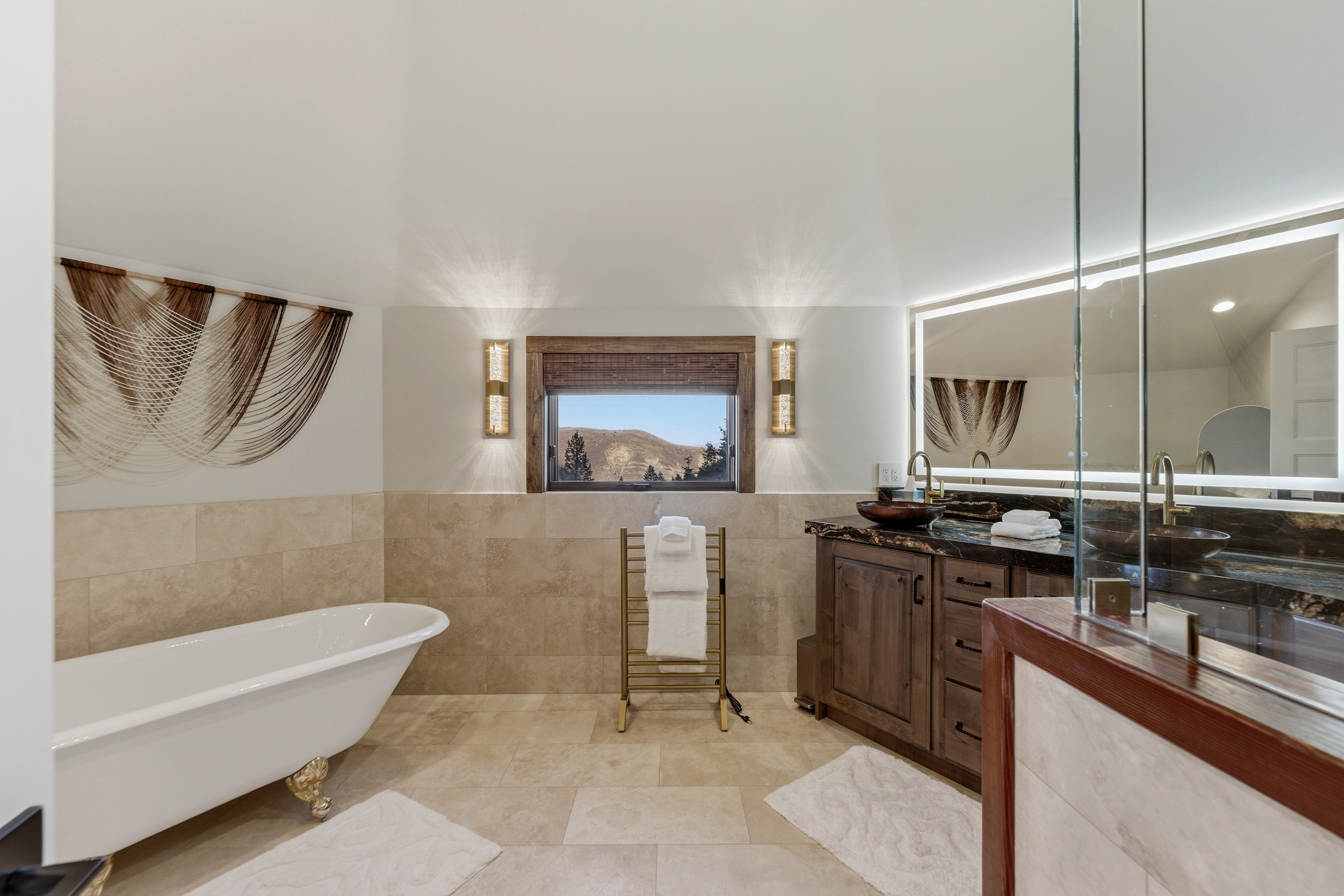 Full bathroom featuring vanity, a freestanding tub, a wainscoted wall, tile walls, and light tile patterned floors