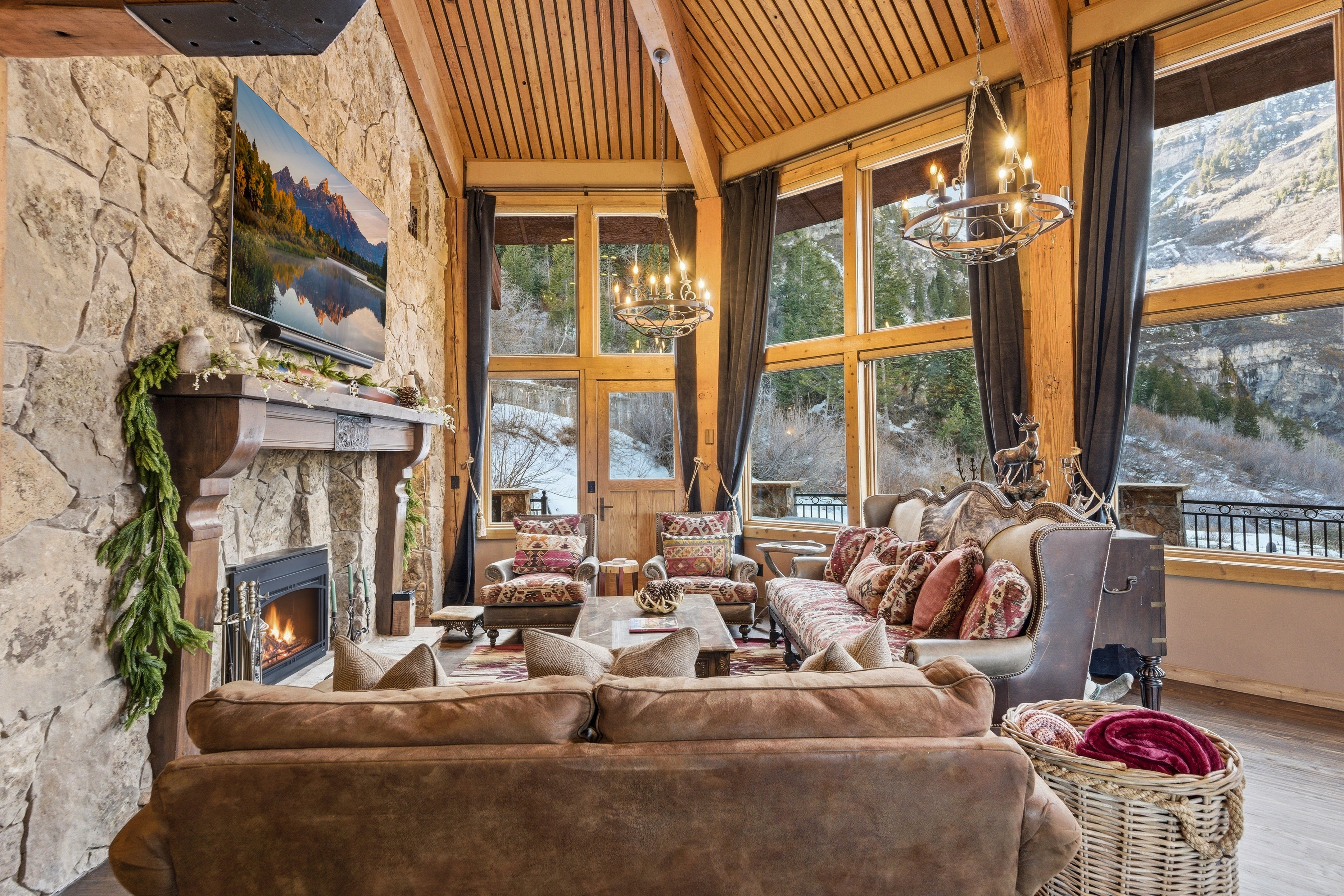 Living room with hanging lights, a vaulted wood ceiling, wood finished floors, a fireplace, and plenty of natural light
