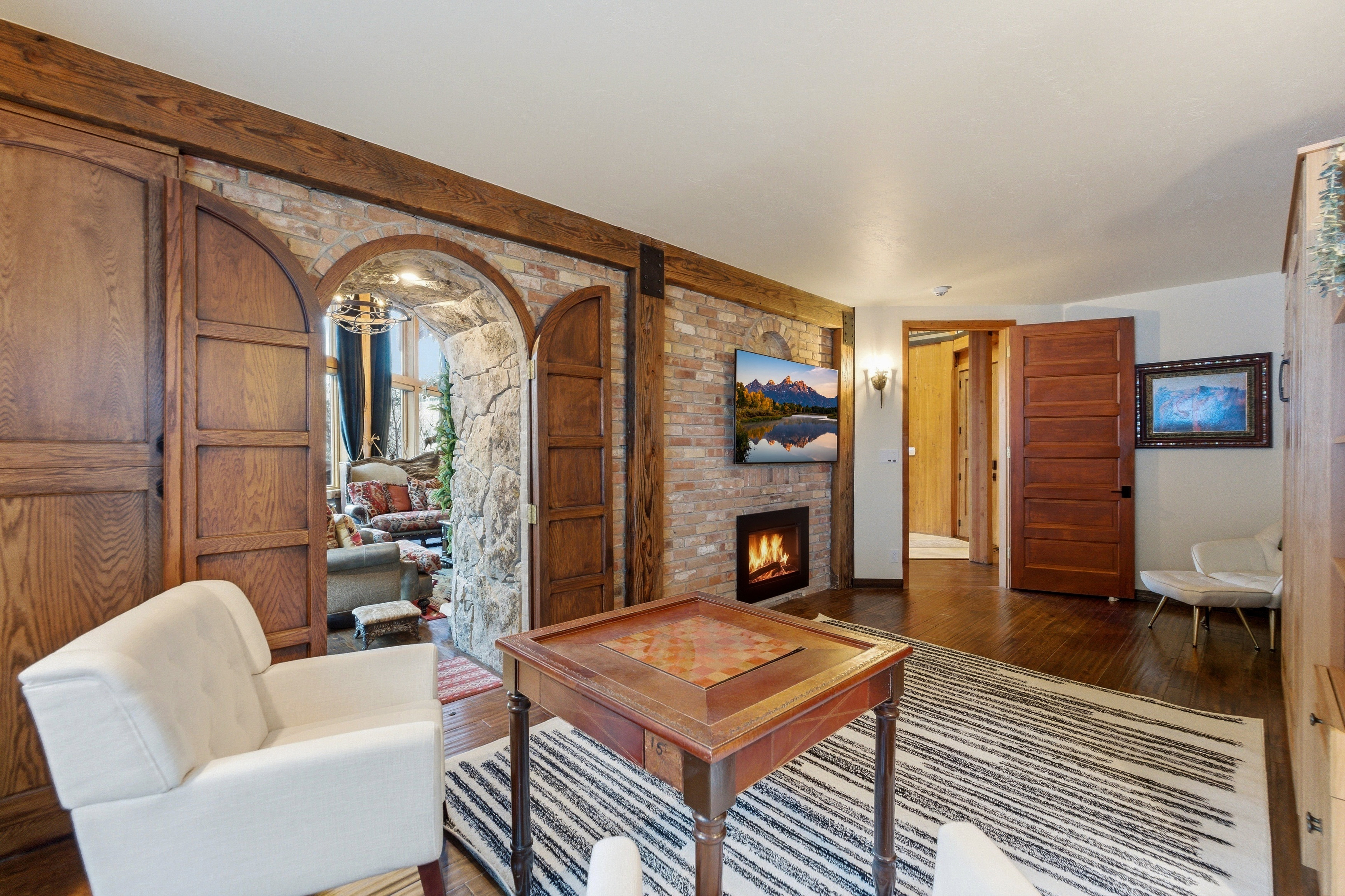 Living room with wood-type flooring, a brick fireplace, and arched walkways