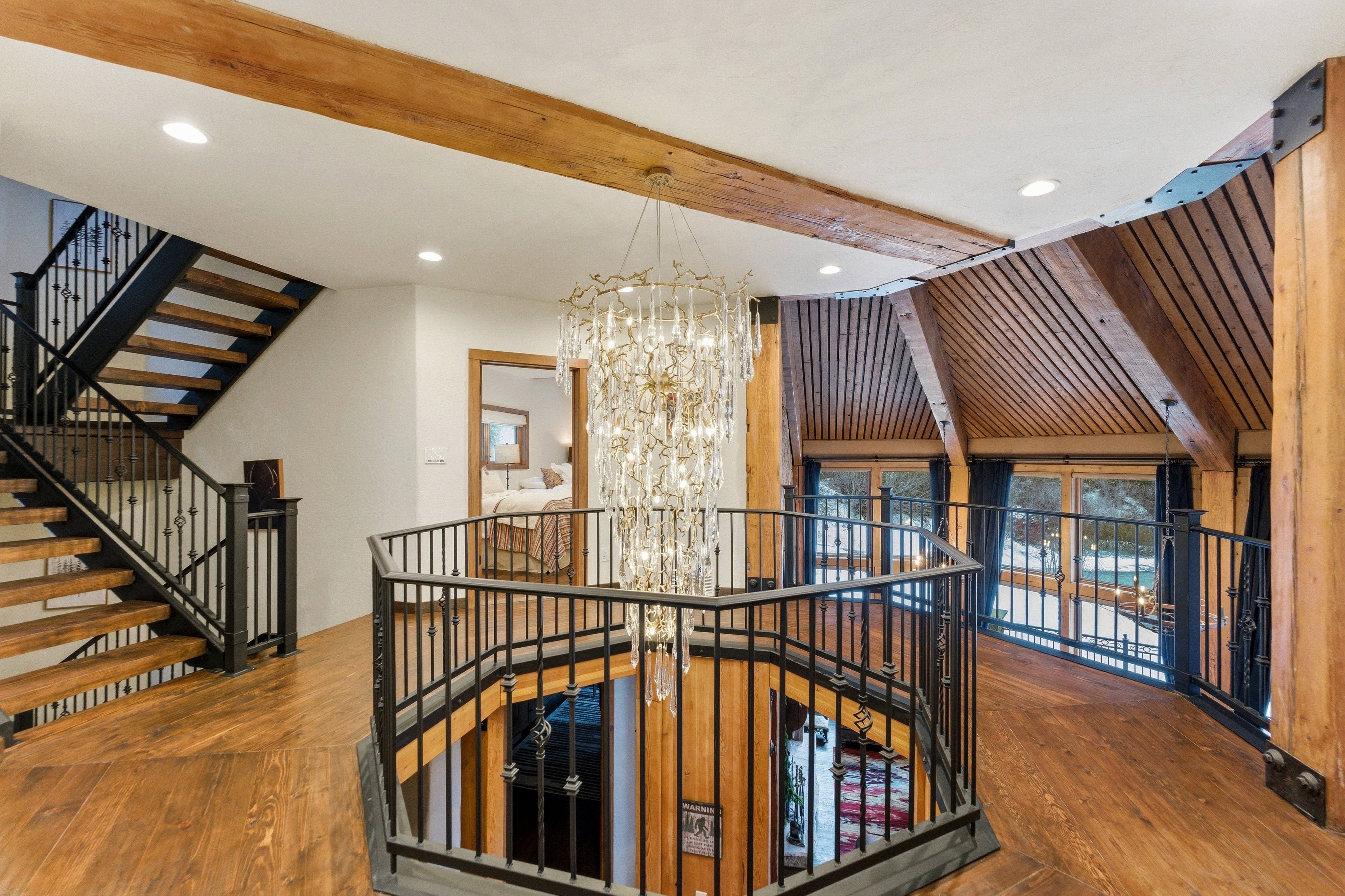 Staircase with suspended lighting, beamed ceiling, and wood-type flooring