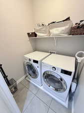 Laundry area featuring light tile patterned floors and separate washer and dryer