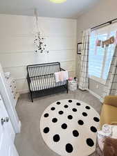 Bedroom featuring a nursery area and light carpet
