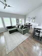 Living room featuring light wood-style floors, vaulted ceiling, and ceiling fan