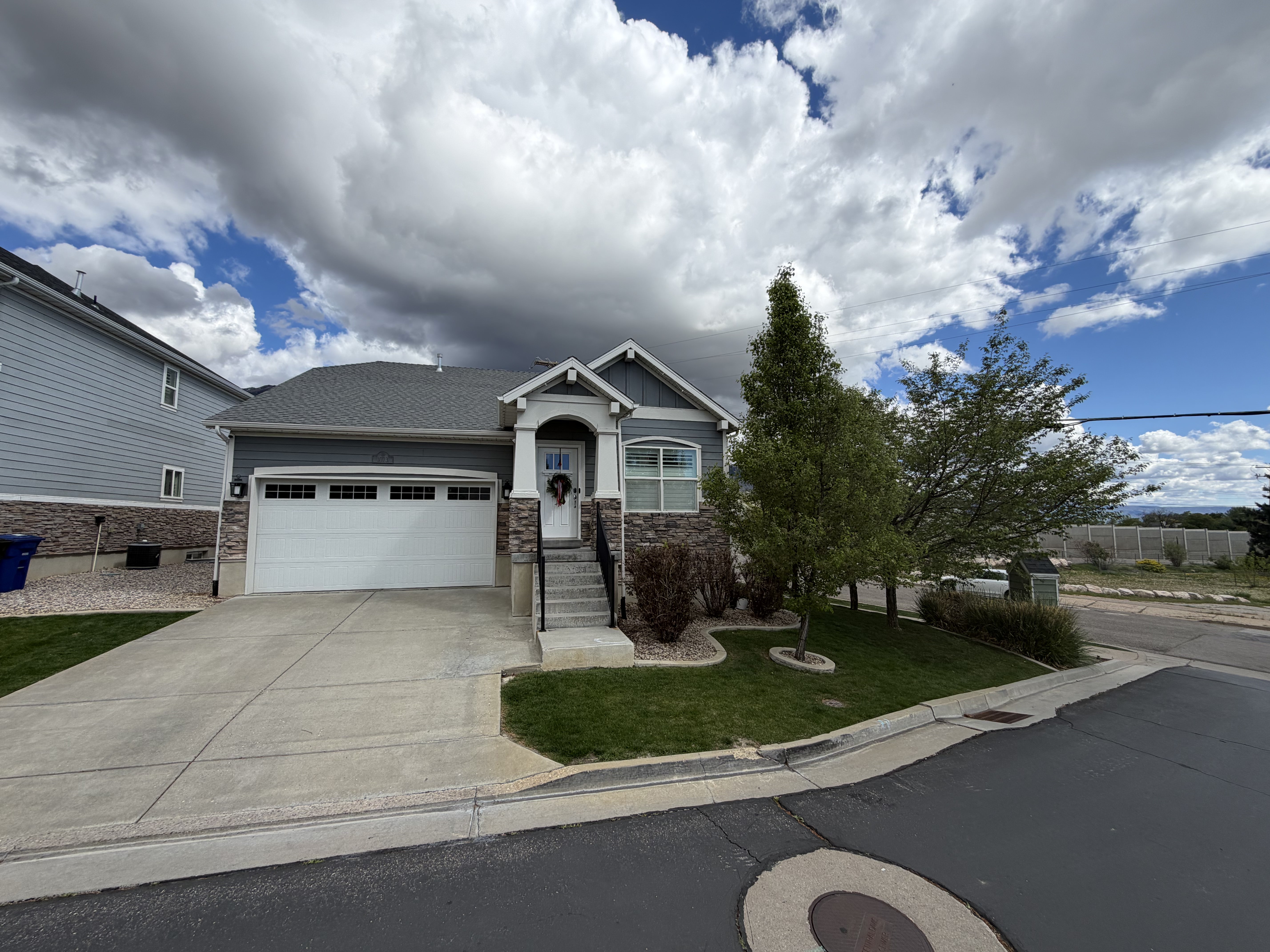 Craftsman house with a garage, driveway, a front lawn, and stone siding