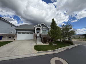 Craftsman house with a garage, driveway, a front lawn, and stone siding