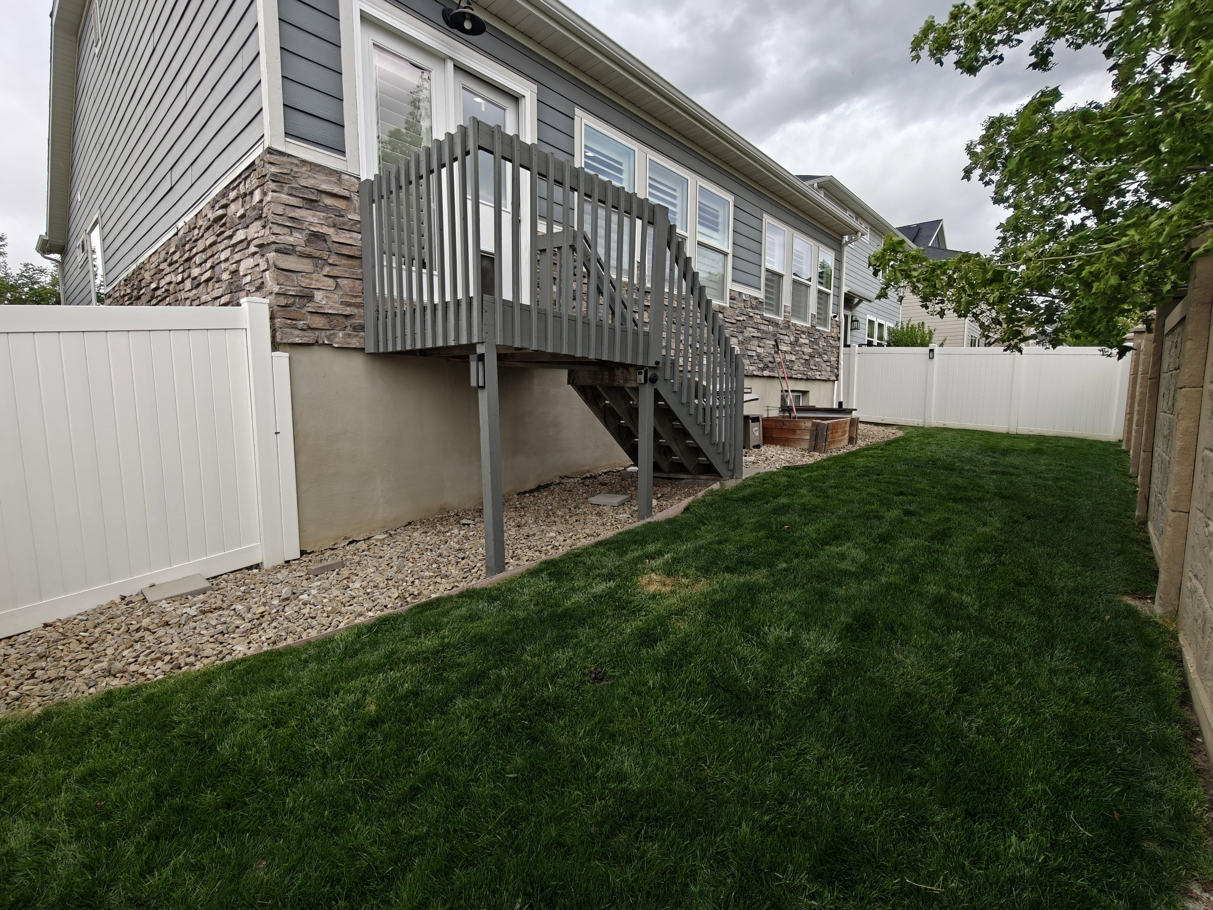 Rear view of property featuring stone siding and a fenced backyard