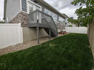 Rear view of property featuring stone siding and a fenced backyard