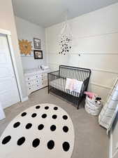 Bedroom with light carpet, a nursery area, and a closet