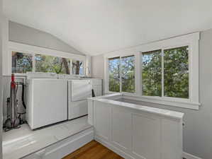 Laundry area featuring dark wood-style floors, lofted ceiling, and washing machine and clothes dryer