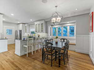 Dining area featuring wood floors, wainscoting, a window seat and a chandelier