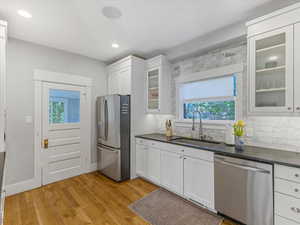 Kitchen featuring stainless steel appliances, plenty of natural light, glass fronted cabinets, white cabinets, and recessed lighting