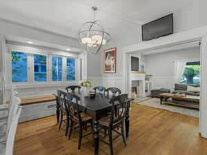 Dining area featuring wood floors, wainscoting, a window seat and a chandelier