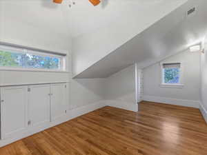 Bonus room with lofted ceiling, light wood finished floors, and ceiling fan