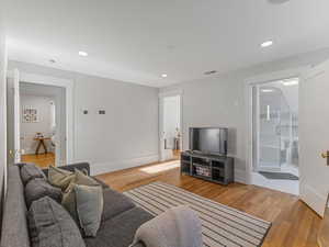 Living area with light wood-type flooring and recessed lighting
