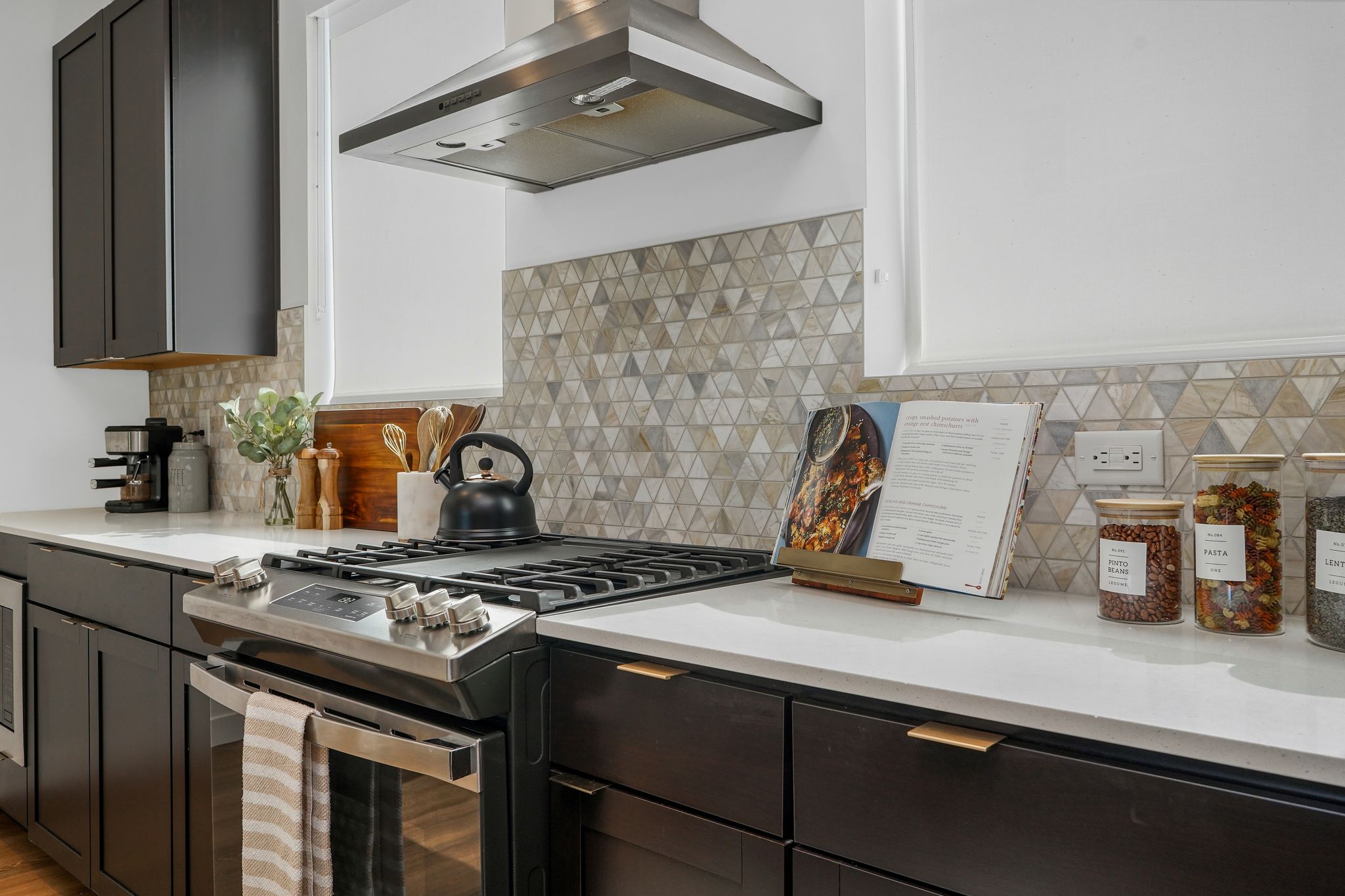 Kitchen with gas stove, island range hood, and light stone countertops