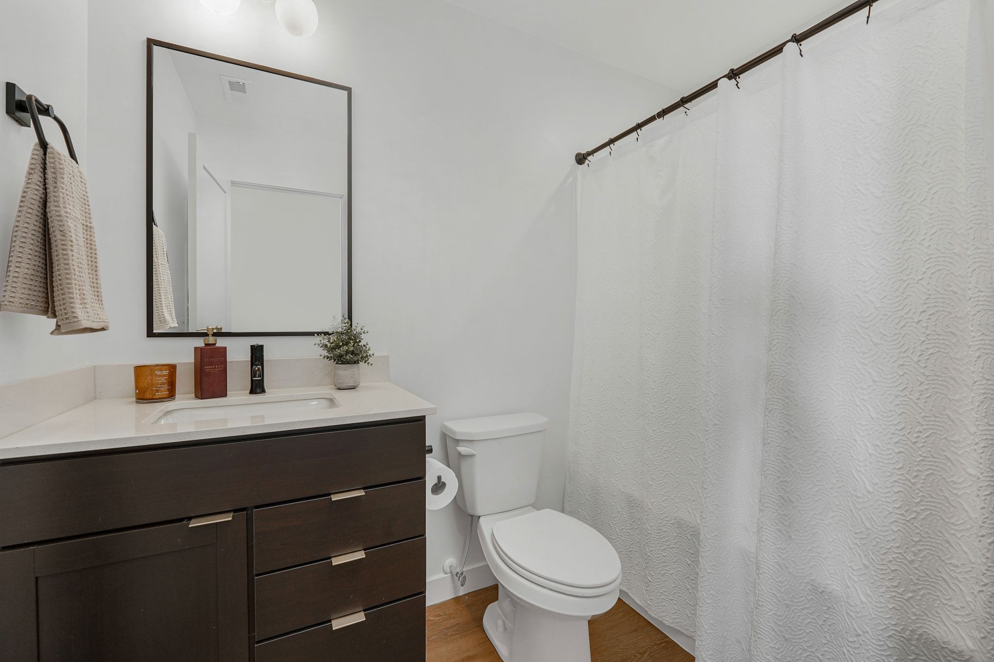 Bathroom featuring curtained shower, vanity, and wood finished floors