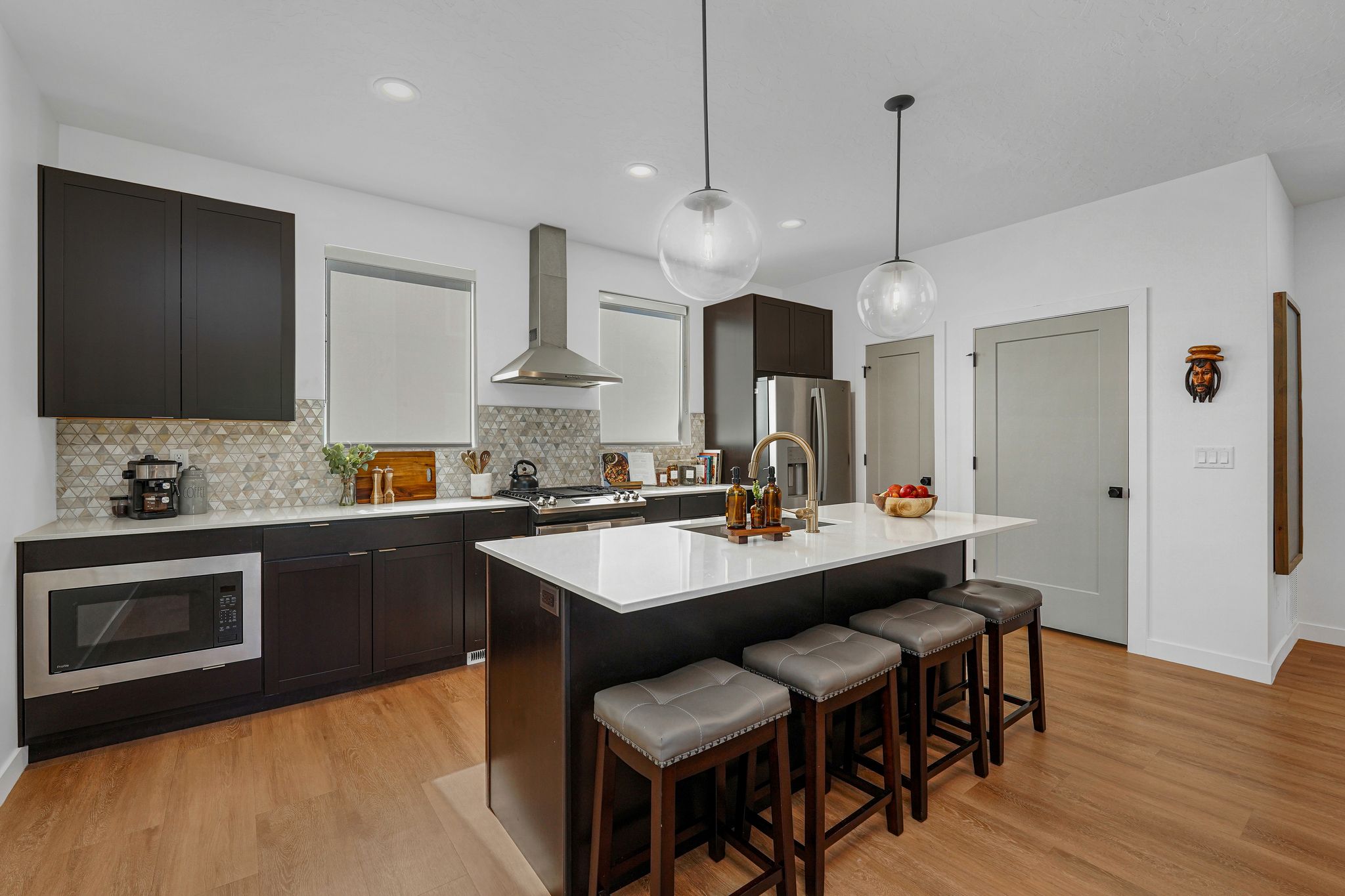 Kitchen featuring light wood-type flooring, stainless steel appliances, hanging light fixtures, and a breakfast bar area