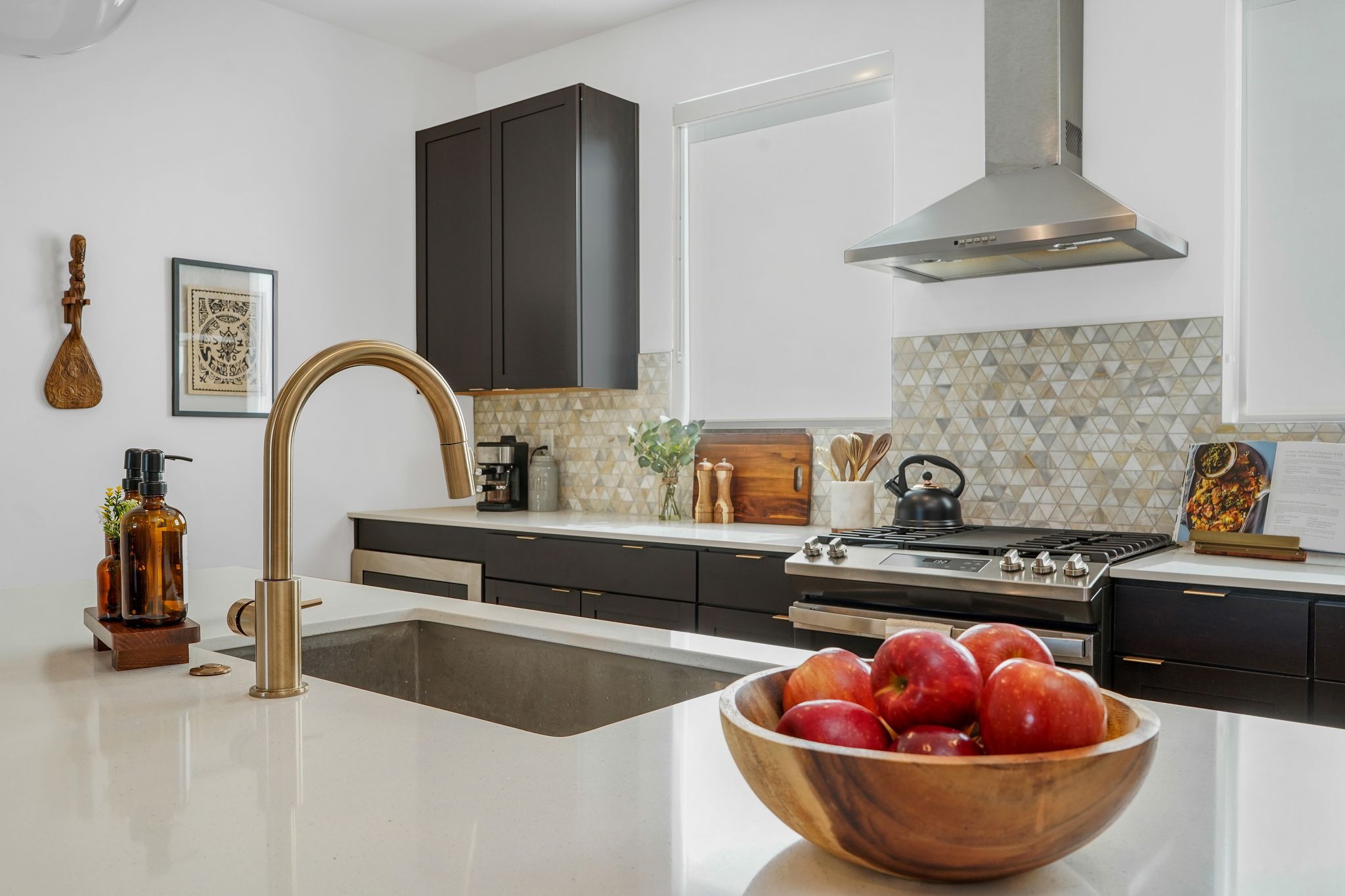 Kitchen with gas stove, light stone counters, and backsplash